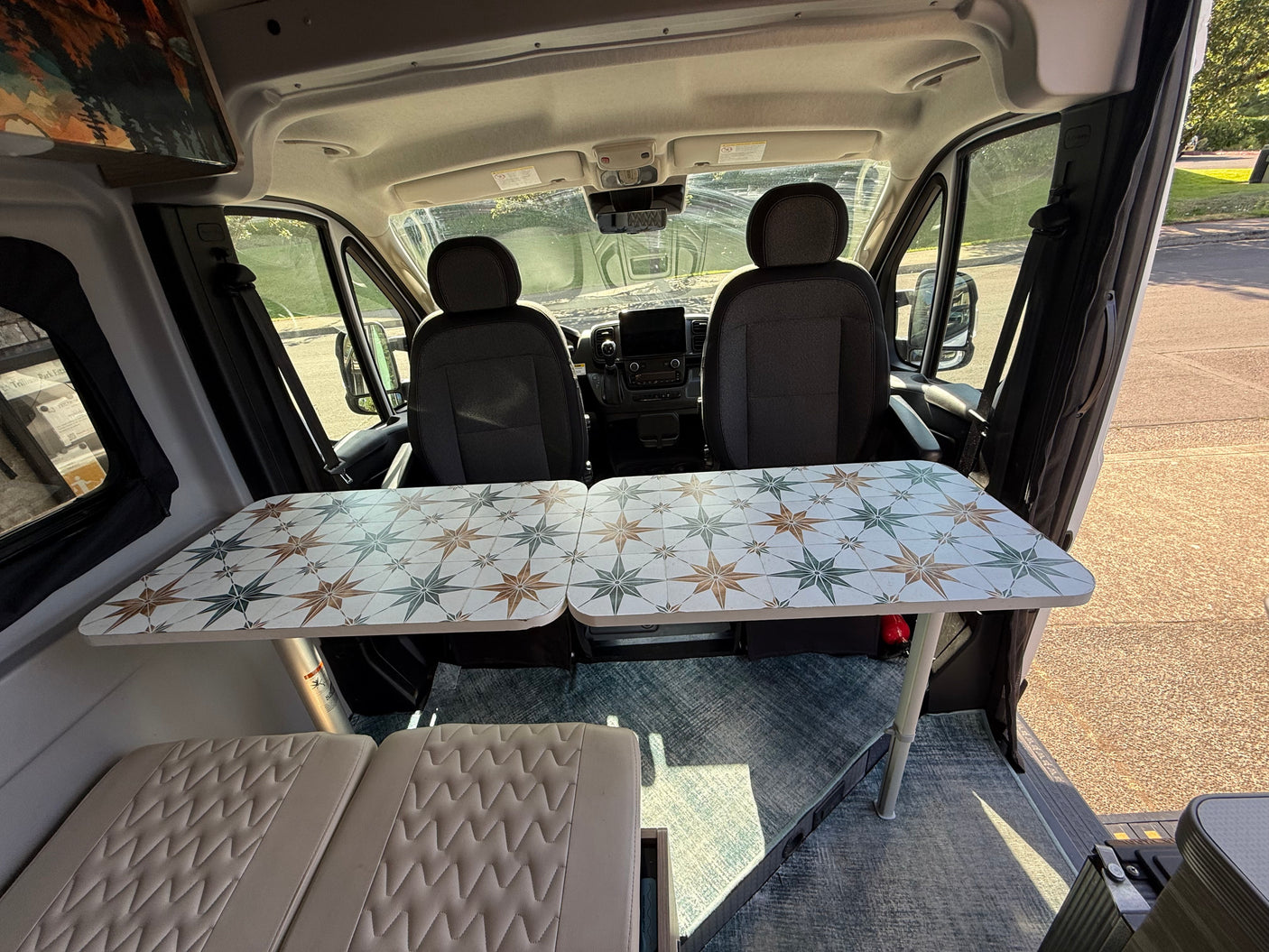 RV rental: Cozy camper van interior featuring a unique star-patterned table, front seats, and comfy cushions.