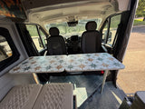 RV rental: Cozy camper van interior featuring a unique star-patterned table, front seats, and comfy cushions.