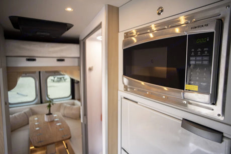 Modern rv rental interior: Stainless steel CONTOURE microwave and dining area for comfortable travel.