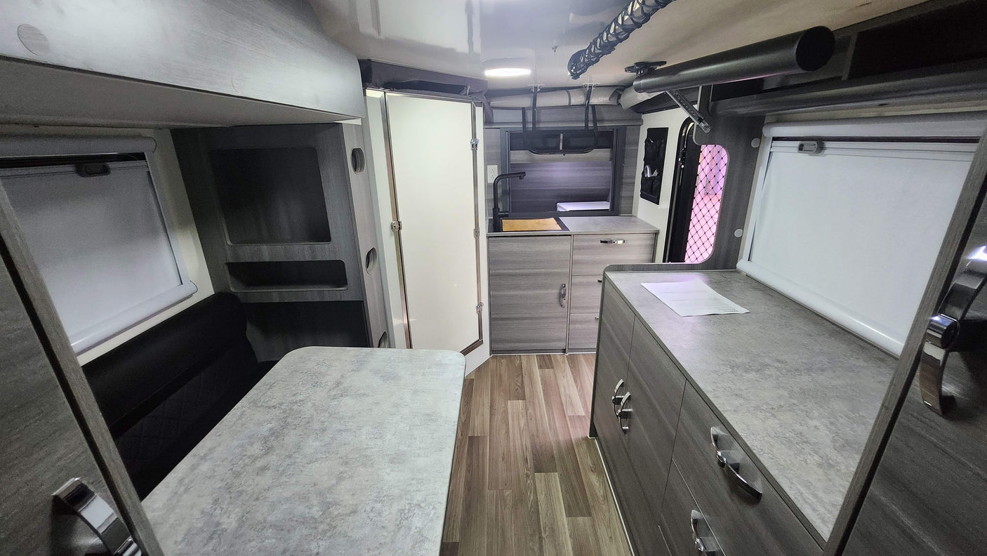 An RV rental's modern interior featuring a compact kitchen, dining area with bench seating, and clever storage solutions.