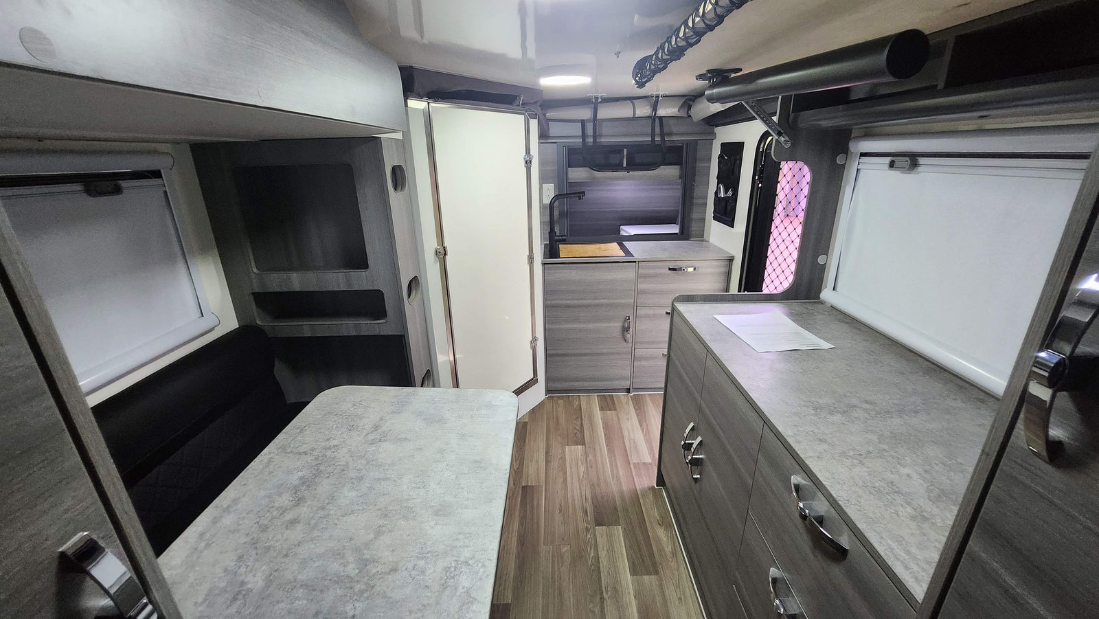 An RV rental's modern interior featuring a compact kitchen, dining area with bench seating, and clever storage solutions.