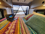 Cozy RV rental interior with bed, laptop, and scenic lake view. Perfect for remote work and travel.