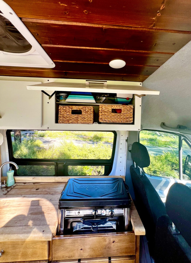 RV rental: Camper van interior with wood ceiling, overhead storage, sink, and a Camp Chef stove on the counter. — photo 13