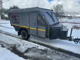Conqueror 4x4 off-road camper trailer on a slushy, snowy road with mountains. Perfect for an adventurous rv rental!