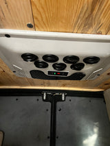 RV rental interior: ceiling AC/heater unit with vents & "20" display, mounted on wooden ceiling above gray vehicle panels.