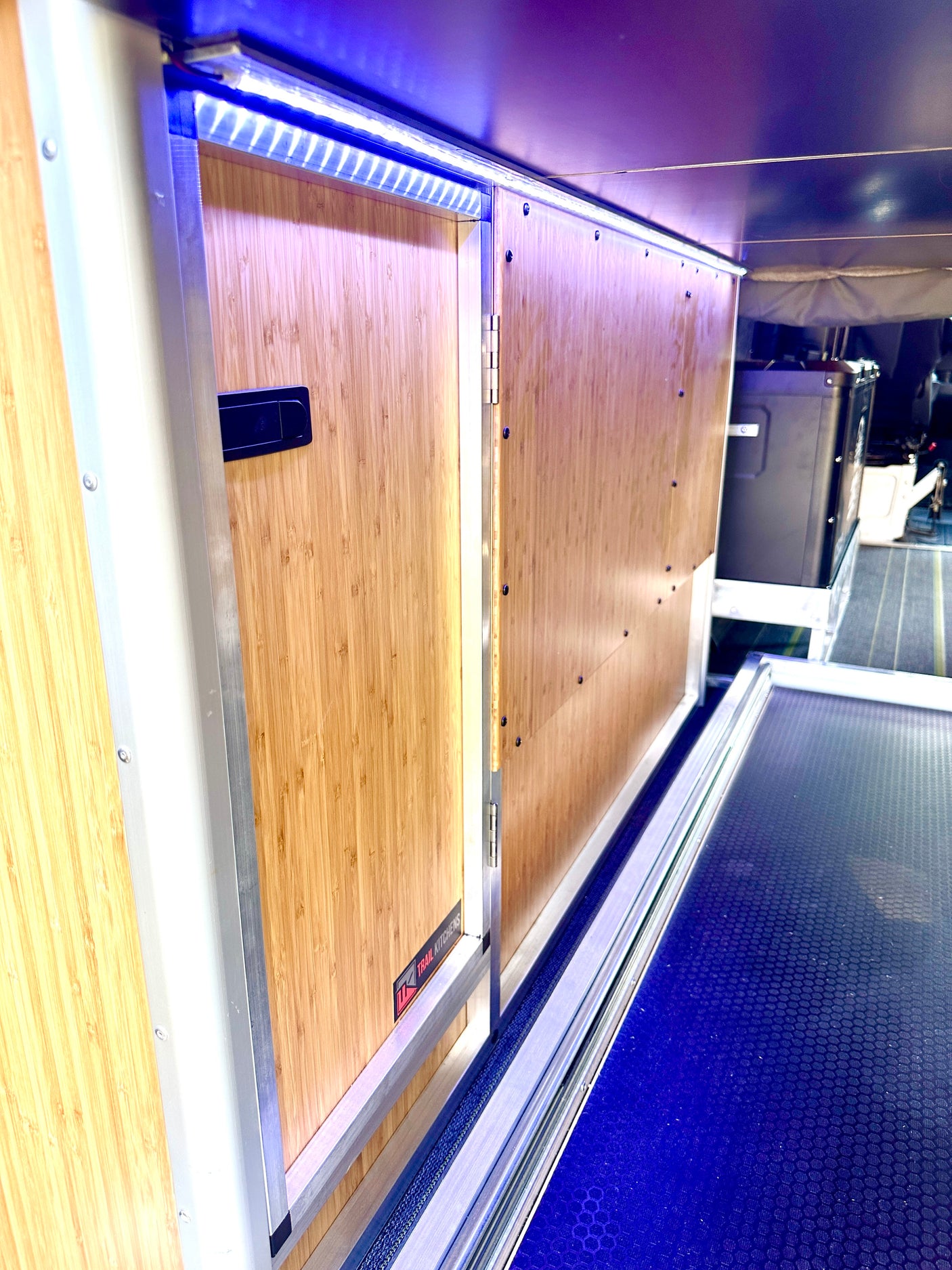 RV rental: View of an RV's custom bamboo kitchen and storage unit with blue LED lighting and pull-out drawer.