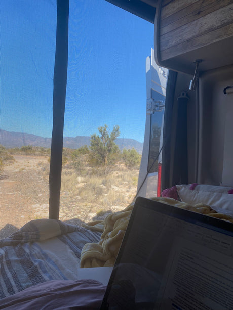 Enjoying remote work from an RV rental, with a laptop overlooking a scenic desert and mountain landscape.