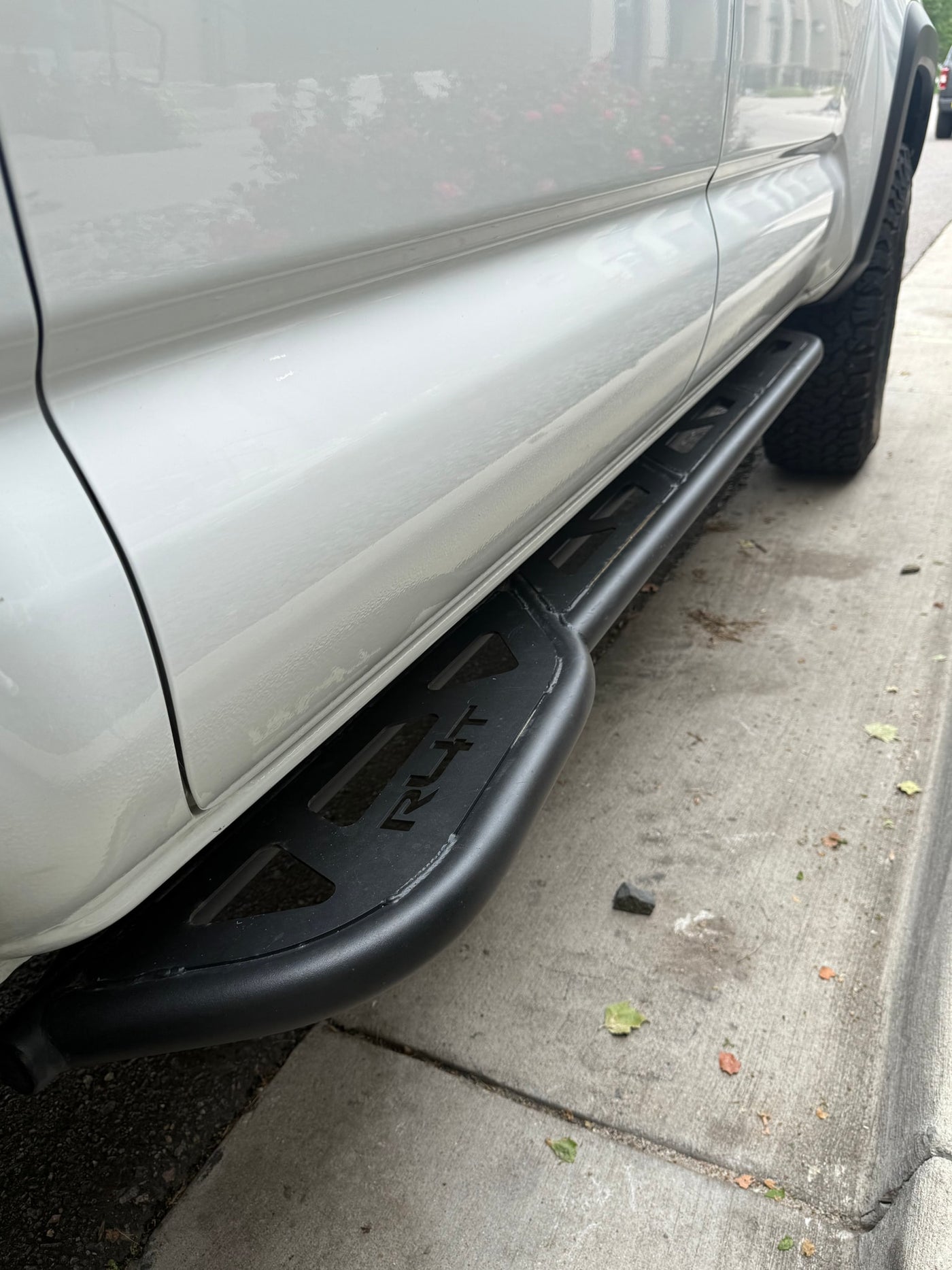 White vehicle with rugged black RLT running boards, parked on concrete. An ideal accessory for any RV rental adventure. — photo 18