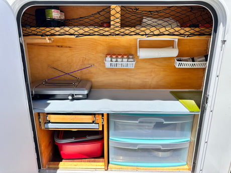 Compact, organized RV rental kitchen setup with stove, spices, and smart storage for camping adventures.