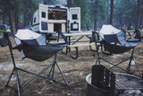 Relaxing at a forest campsite with an RV rental, two hammock chairs, a picnic table, and a fire pit.