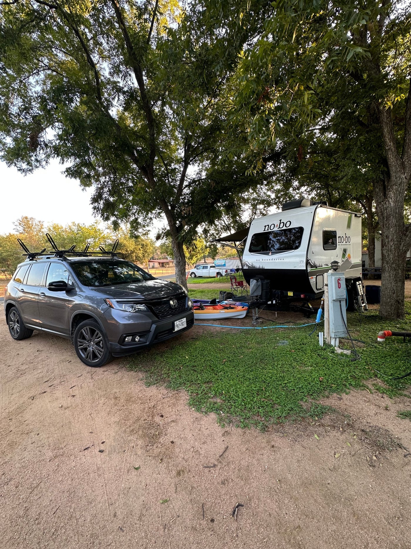 Enjoying the outdoors! An RV rental and SUV with kayaks are set up at a shaded campsite, ready for adventure. — photo 19