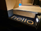 Welcome aboard! An inviting RV rental interior features a "hello" doormat illuminated by a step light.