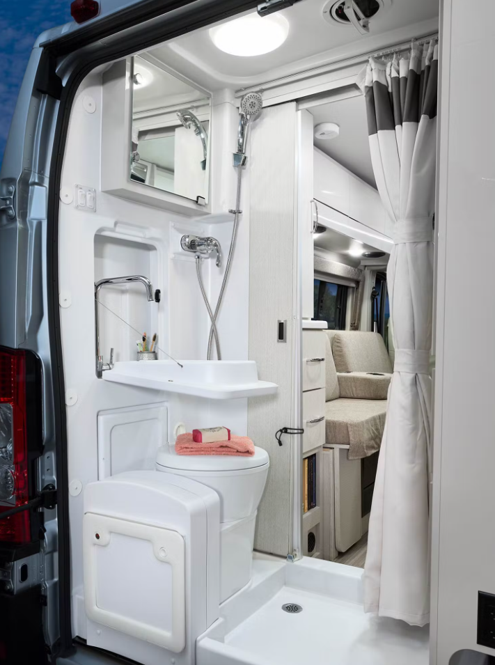 Inside a compact RV rental campervan: integrated wet bath with toilet, fold-down sink, and shower. — photo 16