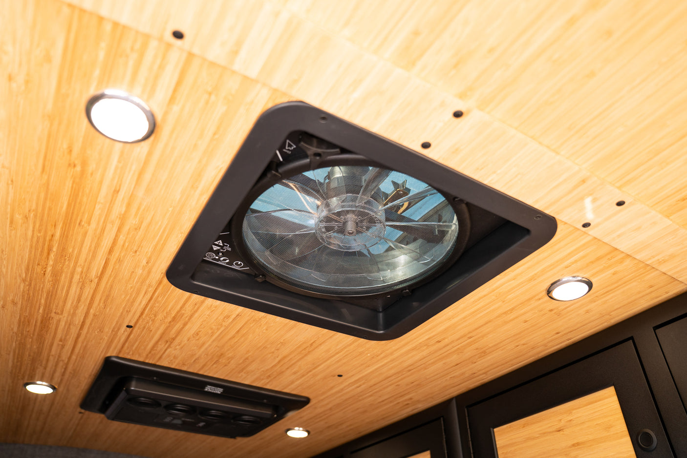 Bright RV rental interior ceiling with a central vent fan, recessed LED lights, and bamboo paneling.
