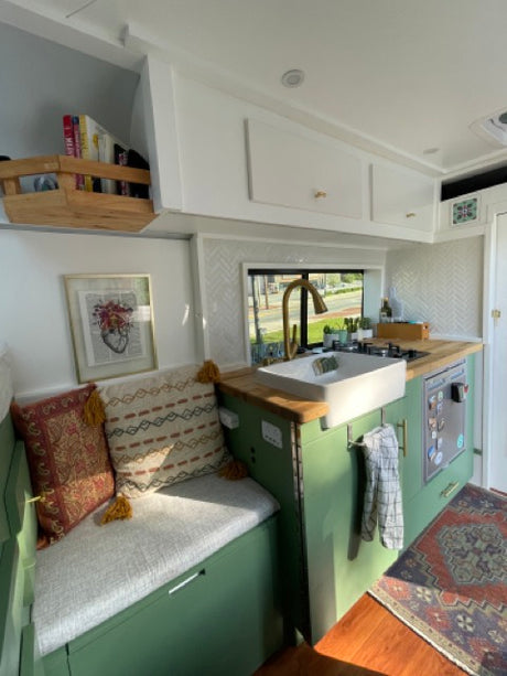 Cozy RV rental interior: green kitchen, bench seating, and window view for a compact travel experience.