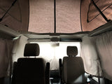 Interior of an rv rental pop-top camper van, featuring front seats, privacy curtains, and a spacious elevated sleeping area.