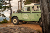 A vintage green Land Rover sits on a mountain lookout. Experience similar outdoor adventures with our RV rental service.