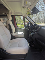 Spacious, light-colored leather interior of a modern camper van, perfect for an RV rental adventure. Shows front seats & dashboard.