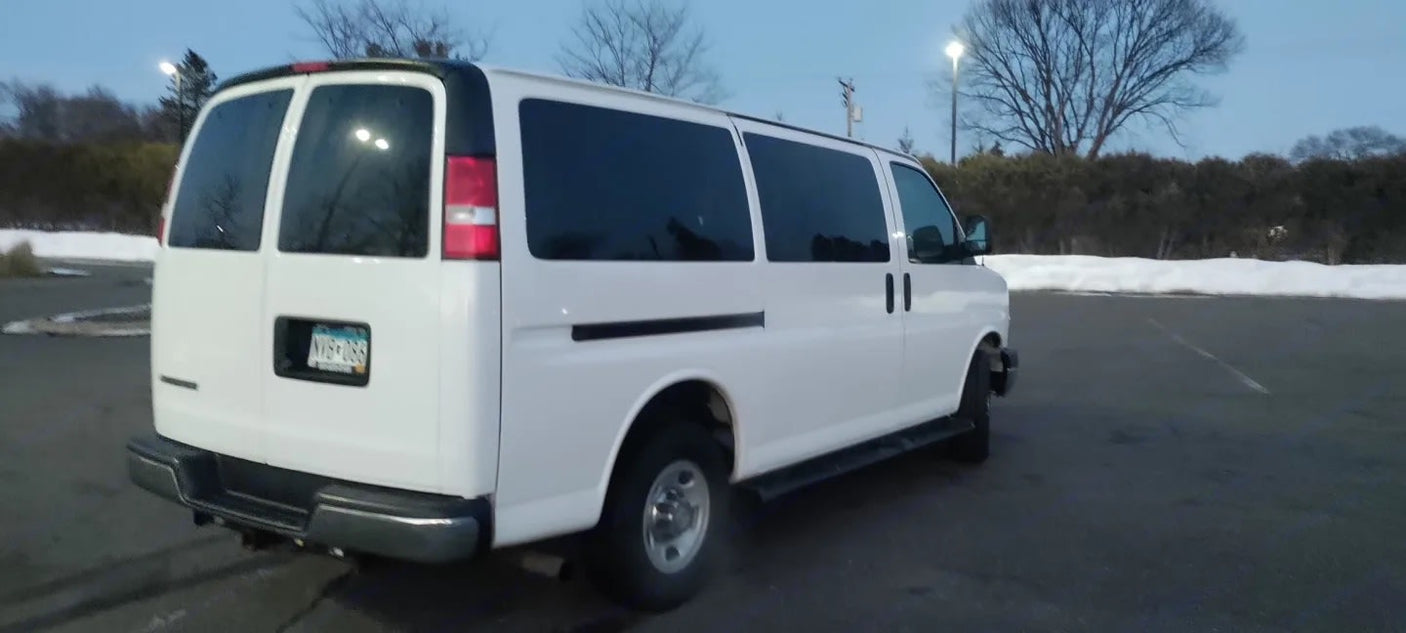 A white passenger van, a perfect RV rental for winter travel, parked in a snowy lot.