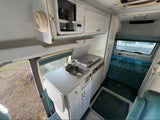 -Functional Sink – Fresh running water for cooking and cleaning.
-Working Propane Stove – Enjoy hot meals without needing an electrical hookup.
- Basic Cooking Gear Included – pot & pan w/ lid, utensils, bowls, plates & cups etc. 

Kitchen with sink, stove, microwave, leading to a rear bed/living area - bed will be made with a 3” memory foam, mattress protector, clean sheets, comforter, & comfortable pillows!