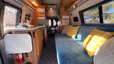 Step into this welcoming RV rental interior! Features a cozy living area with a blue couch, kitchen counter, and bathroom.