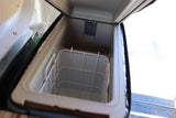 Inside an RV rental's portable cooler, featuring an open lid, interior storage basket, and a spray bottle nearby.