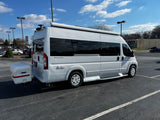 Ultimate Toys RV rental: A white camper van with an awning and rear storage box, parked in a bright outdoor lot.
