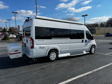 Ultimate Toys RV rental: A white camper van with an awning and rear storage box, parked in a bright outdoor lot.