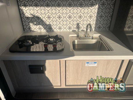 Compact RV rental kitchenette: two-burner stove, sink, and stylish backsplash. Perfect for your next adventure!