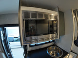 Compact rv rental kitchen: stainless Greystone microwave oven above a small sink. Outdoor view through open door.