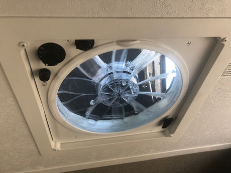 RV rental ceiling fan with adjustable speed and vent controls, plus a protective screen for air circulation.