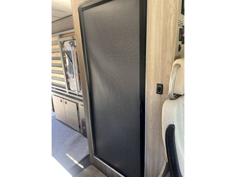 RV rental interior shows a mesh screen door, modern wood cabinetry, and cream seating, offering comfortable campervan travel.