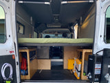 RV rental: Van interior with an elevated bed, under-bed storage units, and a Gasland water heater, perfect for camping.