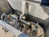 Two propane tanks with a regulator visible in a metal RV rental storage compartment.
