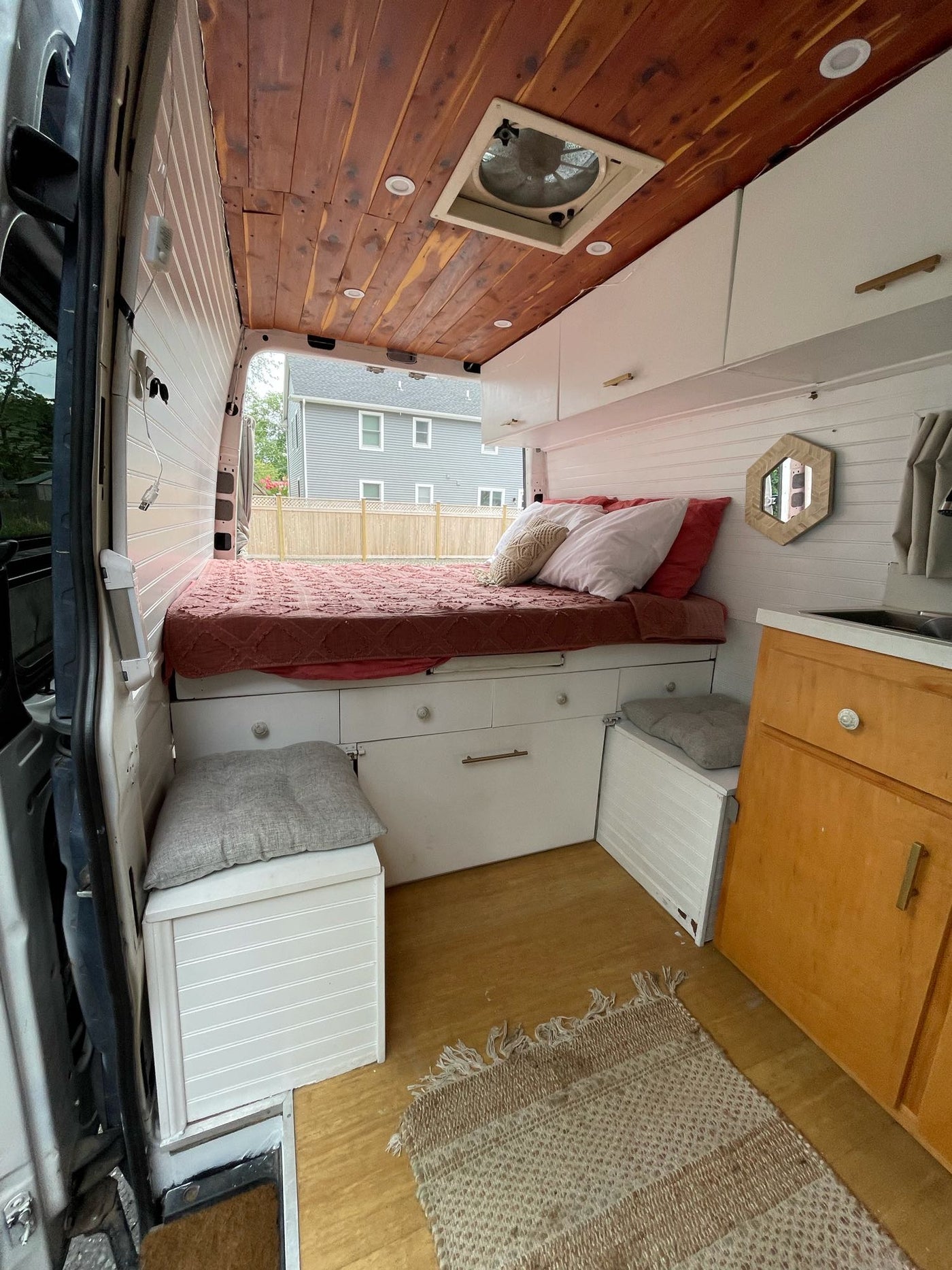 Cozy RV rental interior: bed with storage, overhead cabinets, wood ceiling, and a compact kitchen area. — photo 3