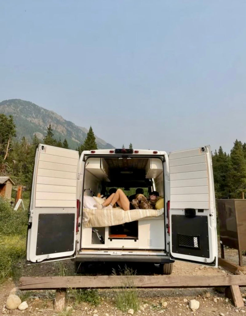  stratified cliffs dominate the background under a clear sky.|RV rental interior features a functional dining/workspace with a laptop — photo 13