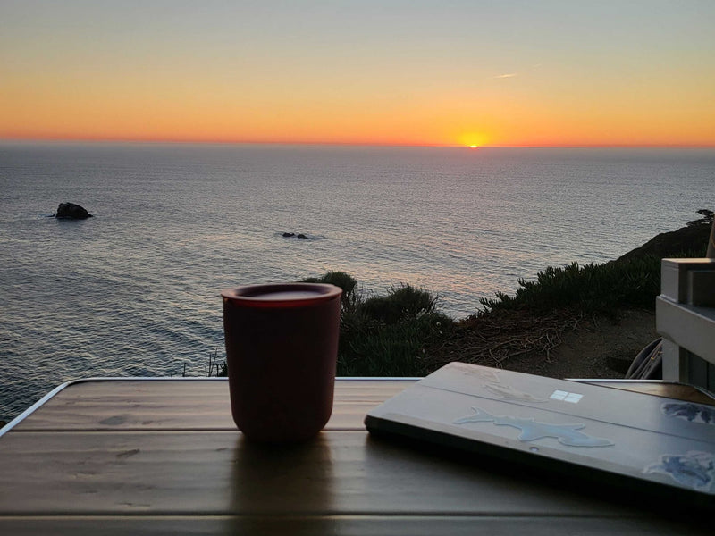 Coastal RV rental sunset: A tranquil workspace with a laptop and mug on a table overlooking the ocean. — photo 13