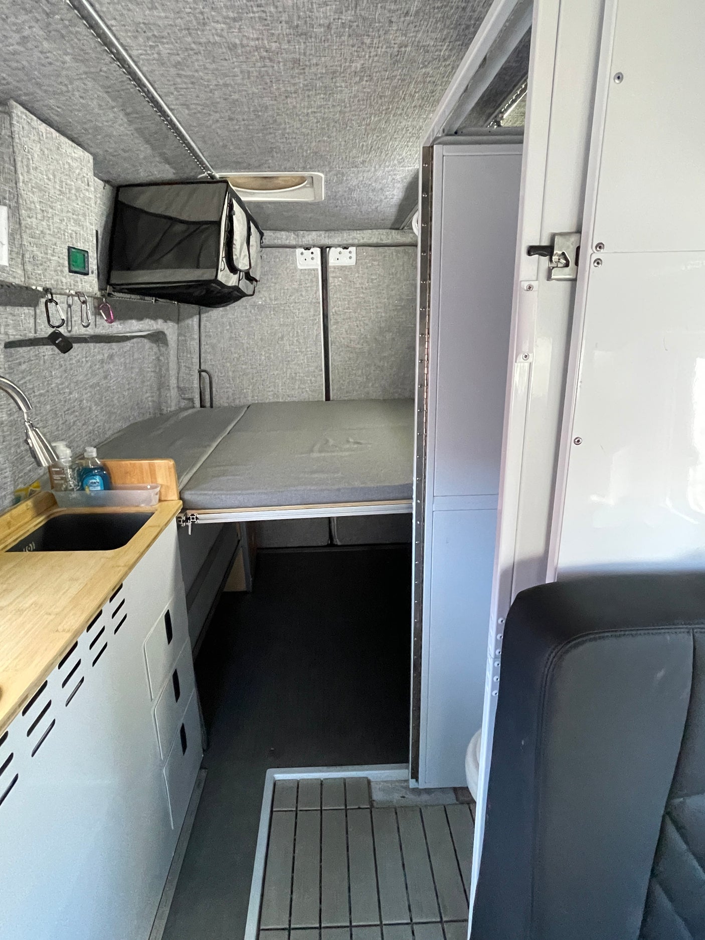 Inside a functional RV rental: compact kitchenette, elevated sleeping area, & clever storage in a modern design.