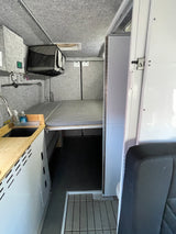 Inside a functional RV rental: compact kitchenette, elevated sleeping area, & clever storage in a modern design.