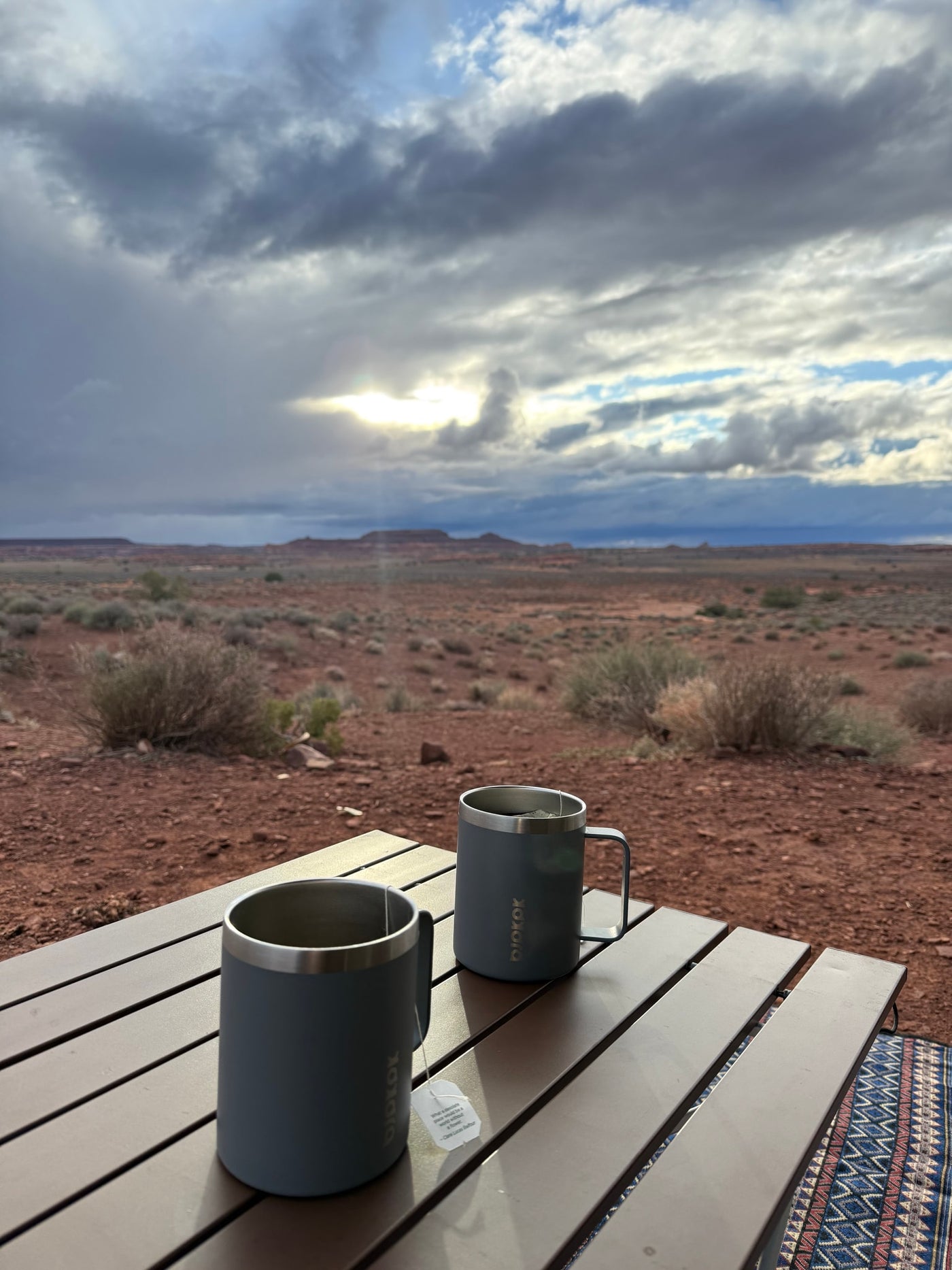 Two mugs of tea on a table, enjoying the vast desert landscape under a dramatic, cloudy sky from our RV rental. — photo 7
