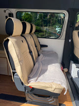 Inside an RV rental: light beige passenger seats with quilted covers, cozy blanket, and outdoor view. Ready for adventure!
