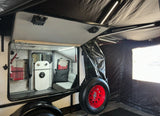 This rv rental's open side reveals a compact, cozy interior with an attached black tent and a striking red spare tire.