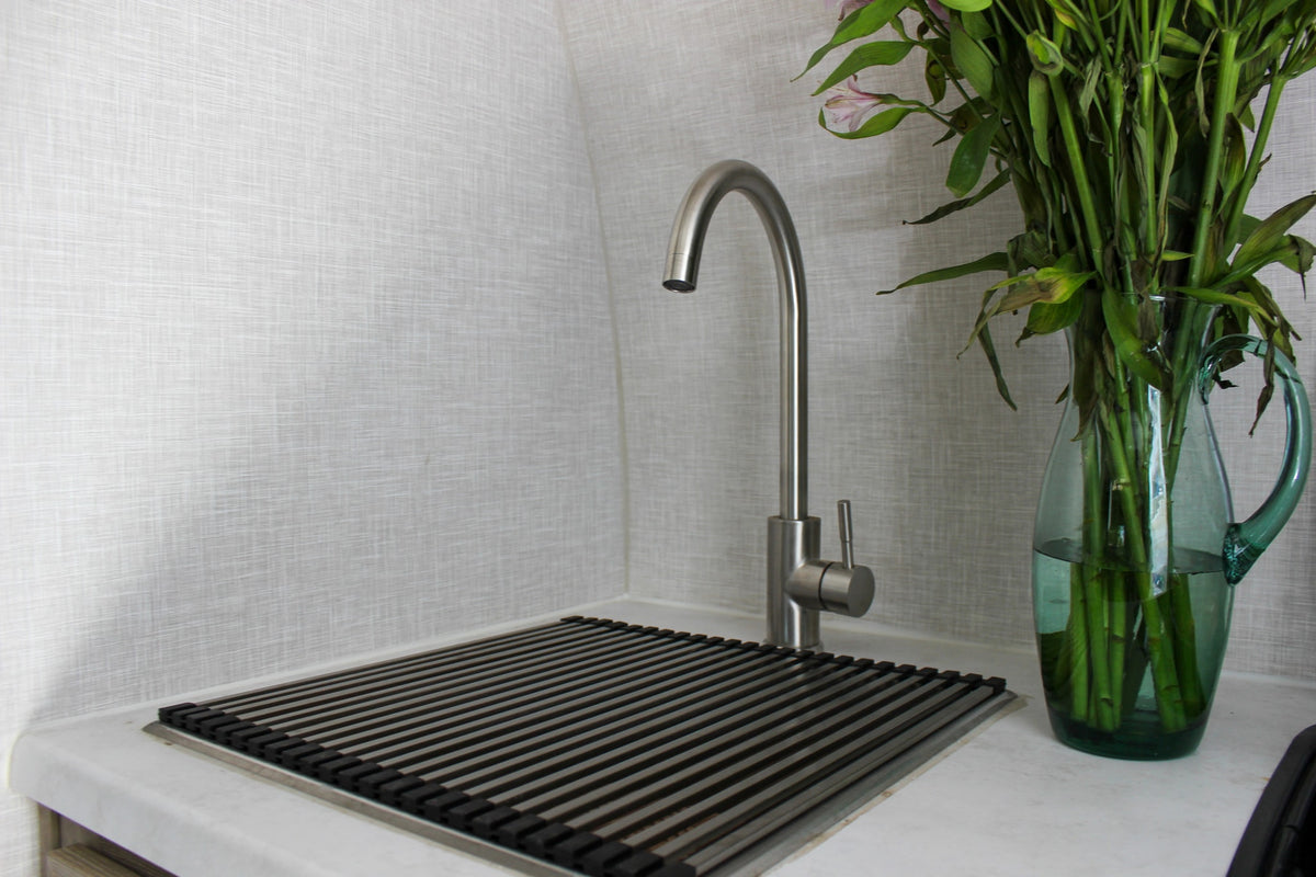 Clean RV rental kitchen area features a brushed metal faucet, a drain rack, and a glass vase with green plant stems. — photo 9