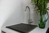 Clean RV rental kitchen area features a brushed metal faucet, a drain rack, and a glass vase with green plant stems.
