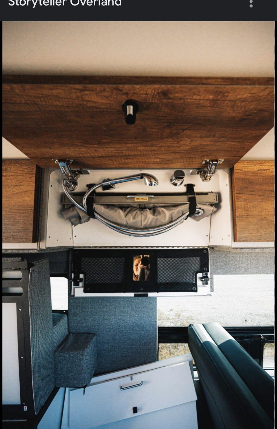 RV interior: Compact pull-out shower, integrated storage, and a reflection of the photographer. Great for an rv rental & mobile living.