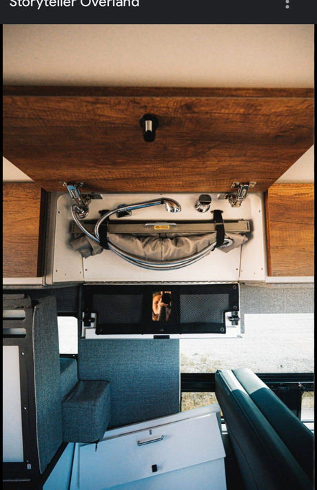 RV interior: Compact pull-out shower, integrated storage, and a reflection of the photographer. Great for an rv rental & mobile living.