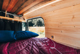 Relax in your RV rental with a comfy bed, wood-paneled walls, and a view of the field. USB charging available.