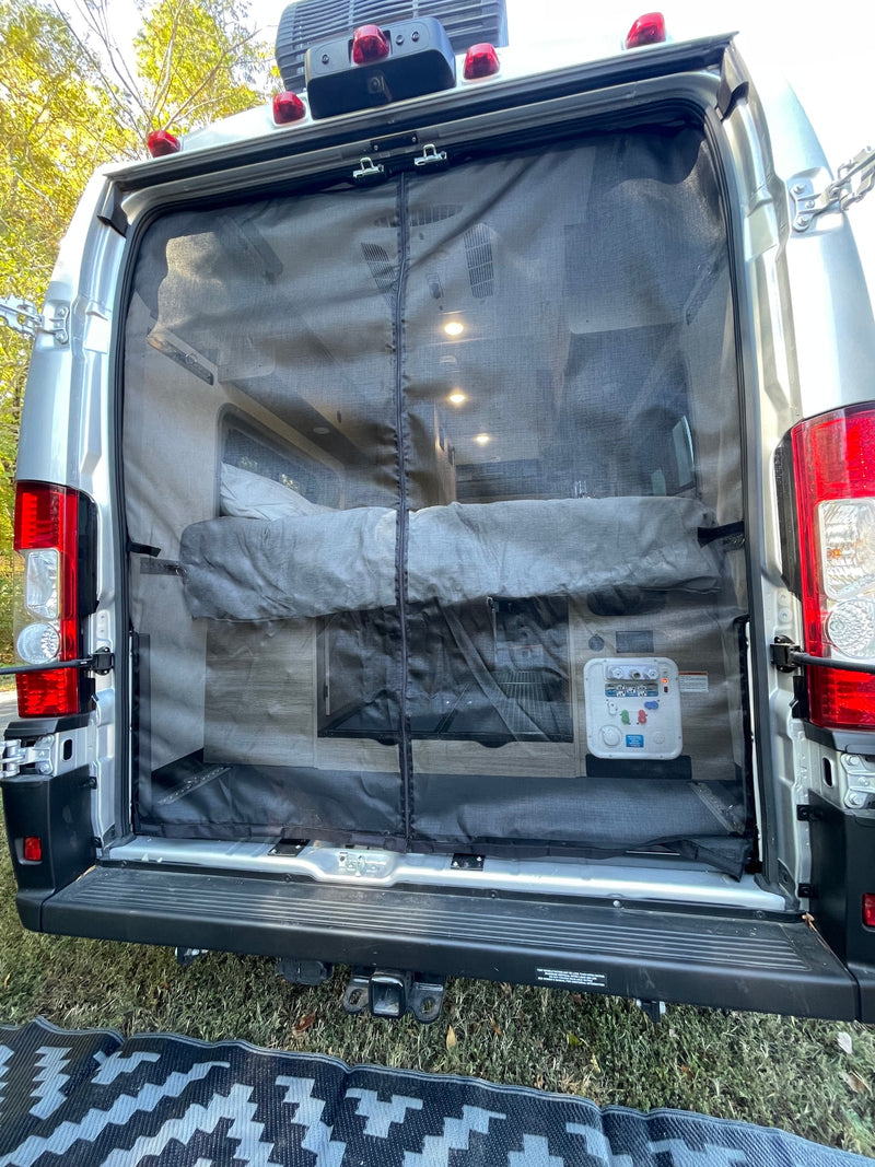 Rear view of an RV rental, doors open with a mesh screen, showing a cozy bed and interior lights, perfect for camping. — photo 10