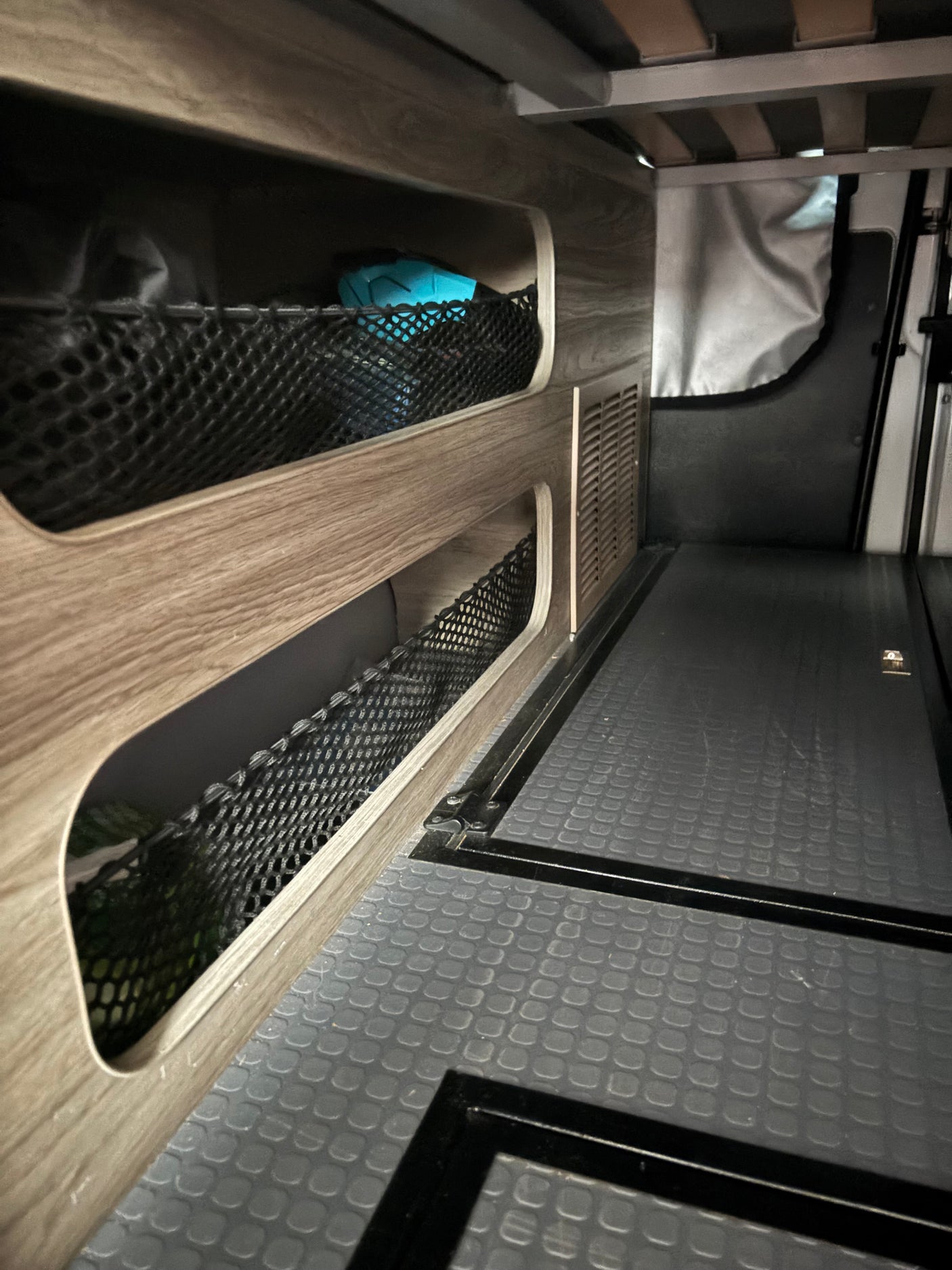 RV rental / camper van interior with mesh storage, slatted bed, vent, and durable floor.