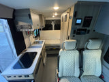 Explore this well-equipped rv rental interior: compact kitchen, modern controls, and comfortable quilted seating area.